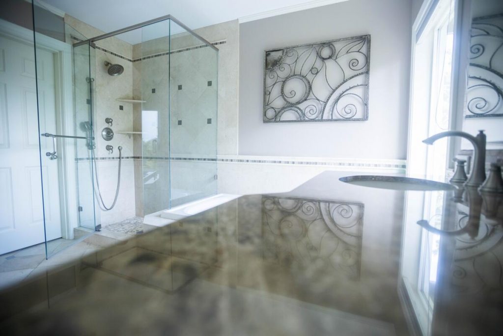 Glass-enclosed shower with granite countertop and decorative wall art