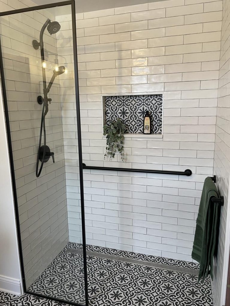 Walk-in shower with white subway tile, patterned cement floor, and matte black fixtures